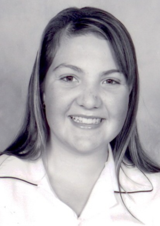 A black and white photo of Kaitlyn smiling. She has straight hair and is wearing a collared shirt